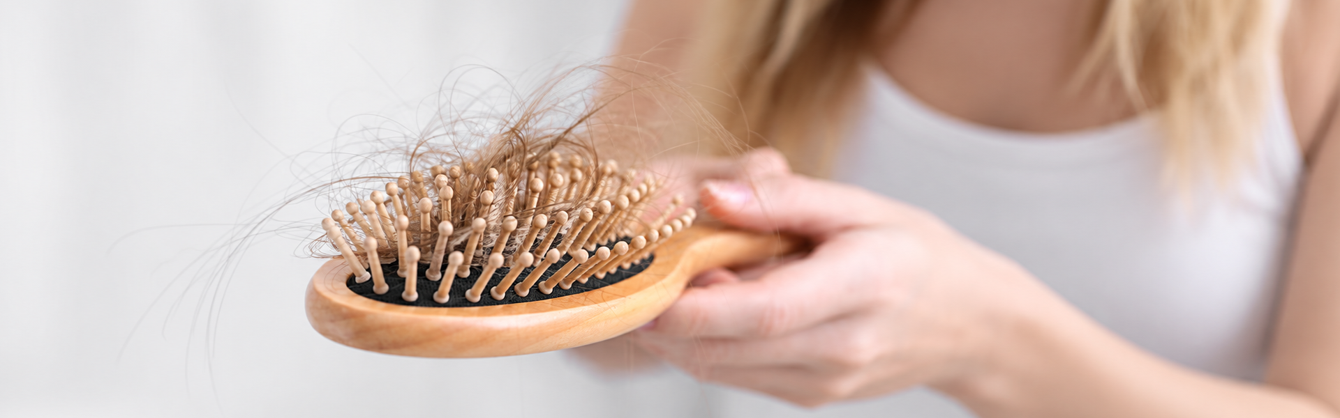 Mujer mostrando cabello acumulado en un cepillo durante la caída del cabello en otoño